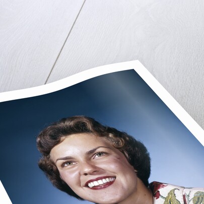 1960s smiling woman in white print dress looking up studio by Anonymous