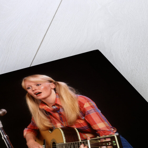 1970s blond young woman ponytails plaid shirt jeans play guitar singing microphone folk singer singers by Anonymous