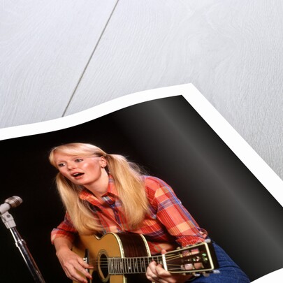 1970s blond young woman ponytails plaid shirt jeans play guitar singing microphone folk singer singers by Anonymous