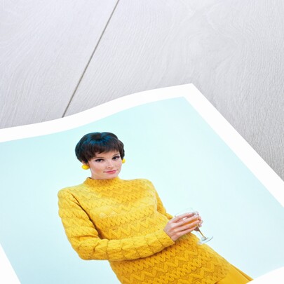 1960s brunette woman short pixie hair style yellow knit sweater earrings holding wine glass by Anonymous