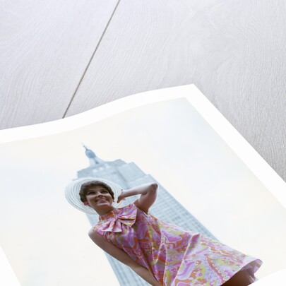 1960s young woman print miniskirt dress summer hat in front empire state building new york city by Anonymous