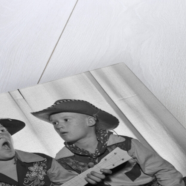 1950s 2 juvenile boys in cowboy hat & shirts playing ukulele & singing mouth open wide by Anonymous