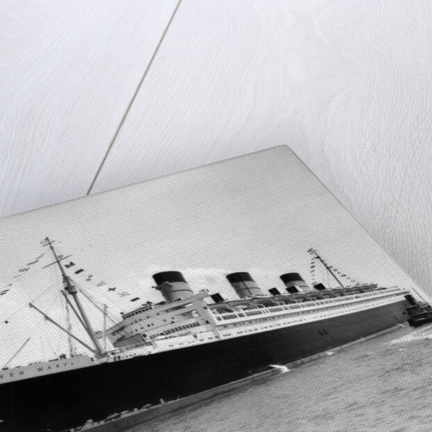 1930s 1936 maiden voyage of queen mary dwarfing small tugboat moving alongside it by Anonymous