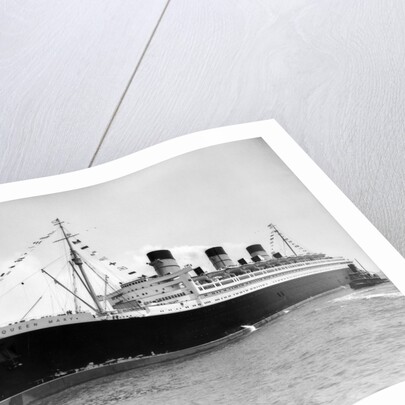 1930s 1936 maiden voyage of queen mary dwarfing small tugboat moving alongside it by Anonymous