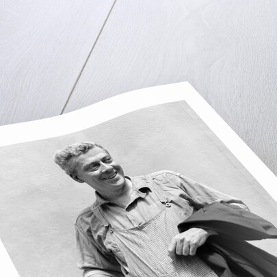 1930s man in overalls work uniform holding thermos lunchbox and jacket by Anonymous