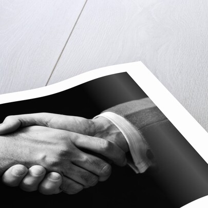 1930s close-up of businessmen's hands in handshake against dark background by Anonymous