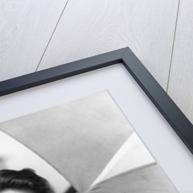 1930s teen girl lying on beach under umbrella wearing bathing suit smiling looking at camera by Anonymous