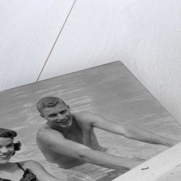1950s teen couple in swimming pool smiling looking at camera by Anonymous