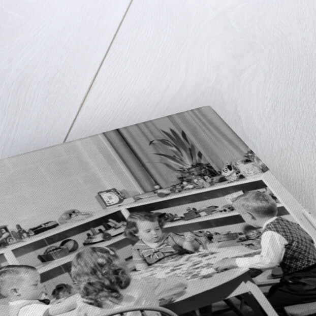 1950s 4 pre-school age children seated at small round table putting together jigsaw puzzle by Anonymous