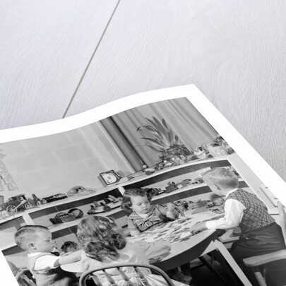 1950s 4 pre-school age children seated at small round table putting together jigsaw puzzle by Anonymous