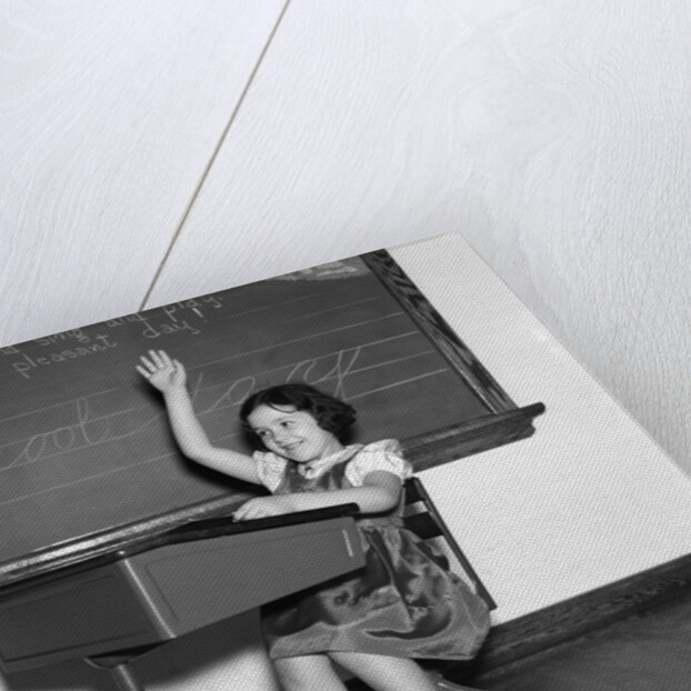 1930s 1940s smiling girl sitting at desk raising her hand by Anonymous