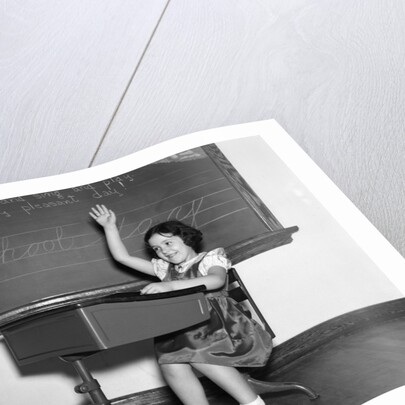 1930s 1940s smiling girl sitting at desk raising her hand by Anonymous