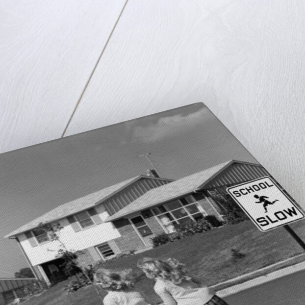 1950s back view of twin girls in plaid skirts & cardigans holding book bags running past school slow sign by Anonymous
