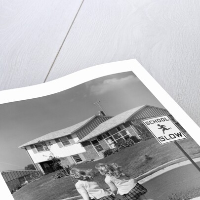 1950s back view of twin girls in plaid skirts & cardigans holding book bags running past school slow sign by Anonymous