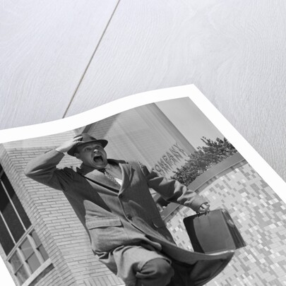 1960s 1950s frantic man running down street holding hat on with hand carrying briefcase wearing top coat by Anonymous