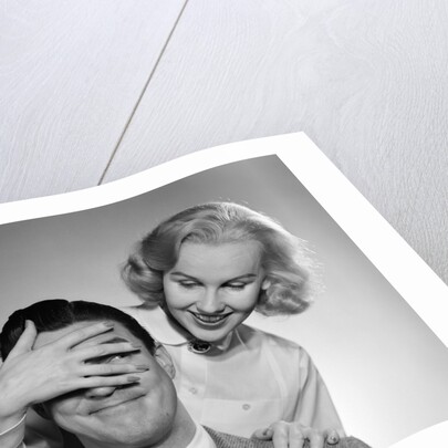 1950s woman standing behind man with hand over his eyes by Anonymous