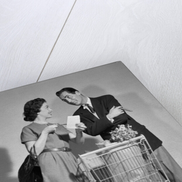1950s couple man woman shopping cart reviewing grocery list man has cigar in hand by Anonymous