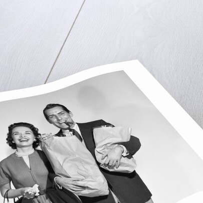 1950s couple smiling woman man carrying grocery bags smoking cigar looking at camera by Anonymous
