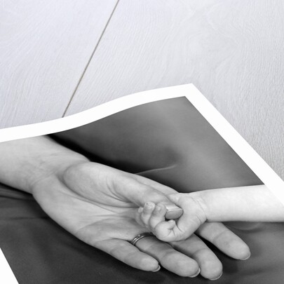 1950s close-up of baby holding mother's thumb by Anonymous