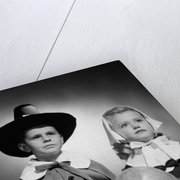 1950s boy & girl in pilgrim costumes with harvest arrangement on table by Anonymous