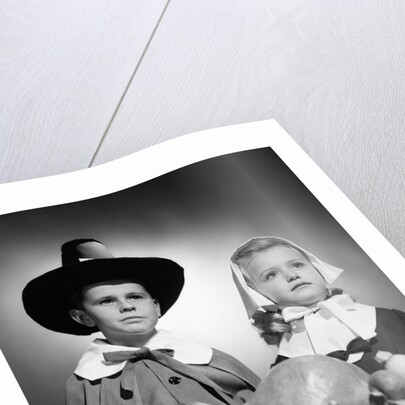 1950s boy & girl in pilgrim costumes with harvest arrangement on table by Anonymous