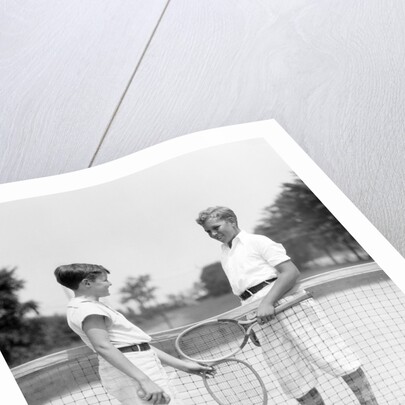 1920s 1930s two boys tennis match holding rackets measuring net height by Anonymous