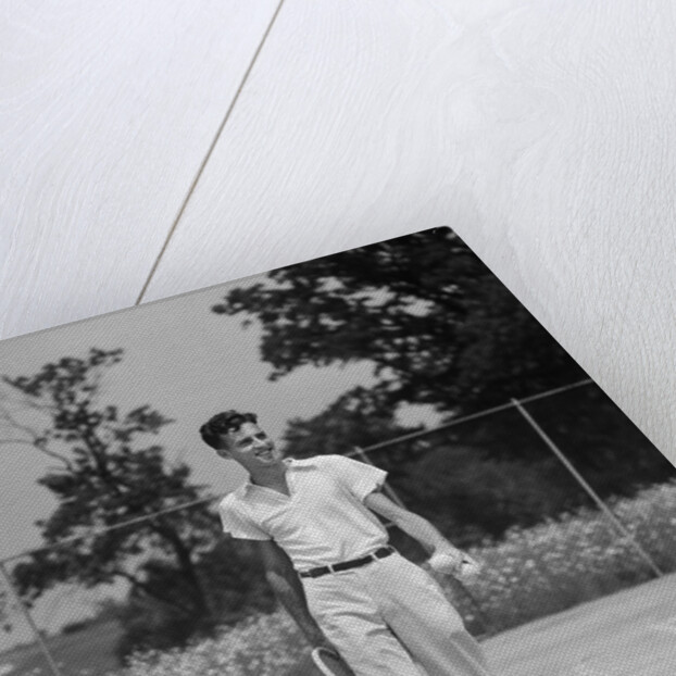 1930s man walking across tennis court holding tennis racket & balls by Anonymous