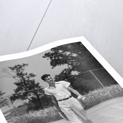 1930s man walking across tennis court holding tennis racket & balls by Anonymous
