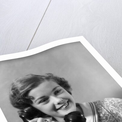 1930s teen girl smiling brunette print dress talking on telephone by Anonymous