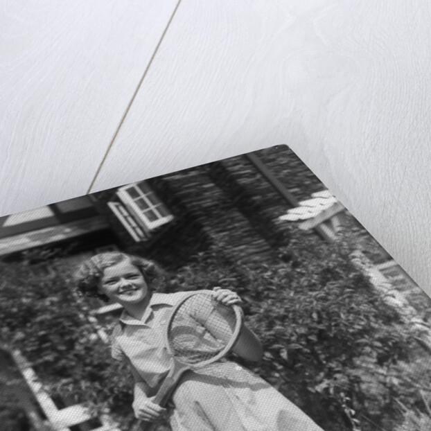 1930s teen girl brunette on sidewalk of house holding tennis racket wearing shorts by Anonymous