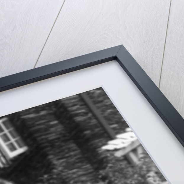 1930s teen girl brunette on sidewalk of house holding tennis racket wearing shorts by Anonymous