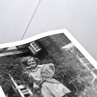 1930s teen girl brunette on sidewalk of house holding tennis racket wearing shorts by Anonymous