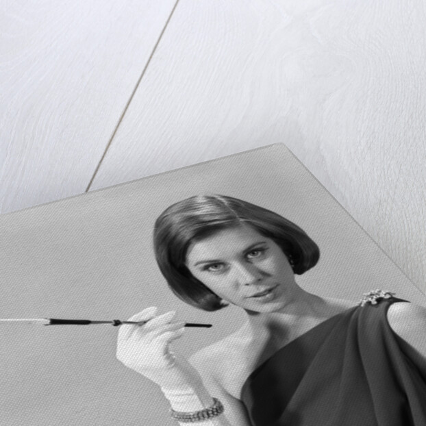 1960s formally elegantly dressed young woman looking at camera with a cigarette holder wearing long white gloves by Anonymous