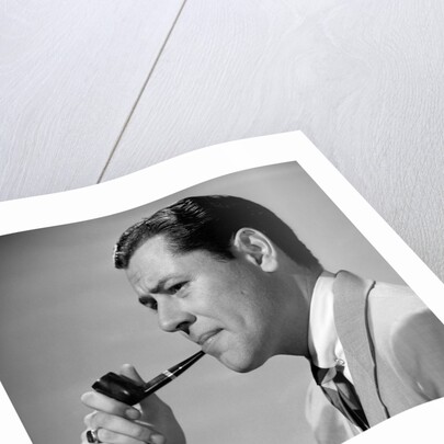 1950s frowning businessman in jacket and tie smoking a pipe by Anonymous