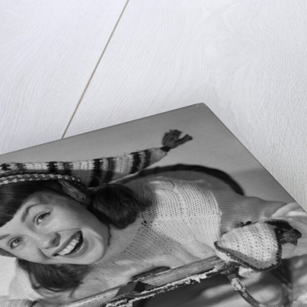 1950s smiling young teenage woman posing on sled in winter wool knit clothes looking at camera by Anonymous