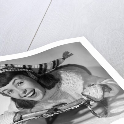1950s smiling young teenage woman posing on sled in winter wool knit clothes looking at camera by Anonymous