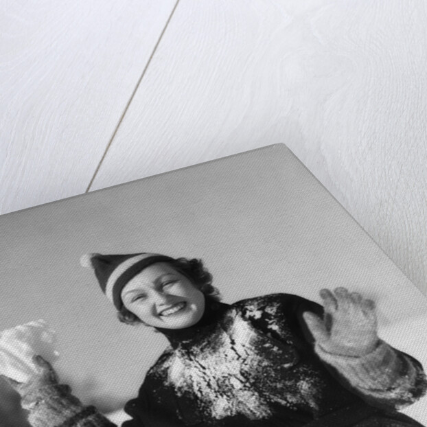 1930s smiling young woman covered in snow throwing piece of snow squinting looking at camera by Anonymous