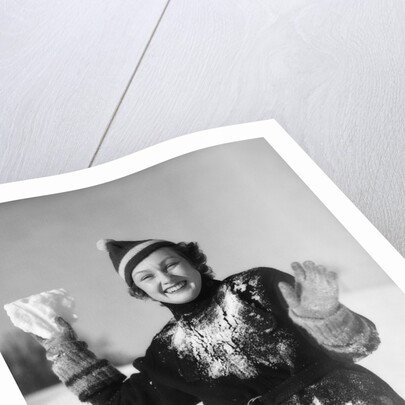 1930s smiling young woman covered in snow throwing piece of snow squinting looking at camera by Anonymous