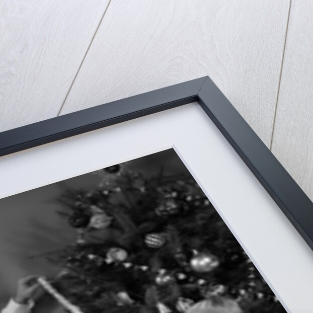 1960s family father mother two sons trimming christmas tree with string of popcorn by Anonymous