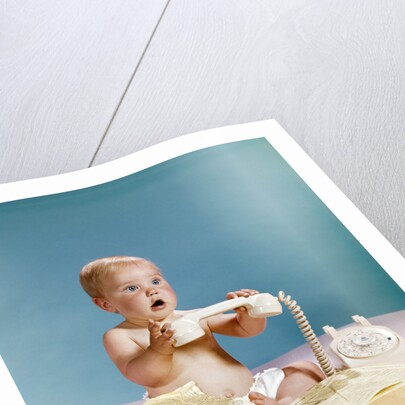 1960s baby surprised facial expression holding telephone hand set over yellow pages phone book directory by Anonymous