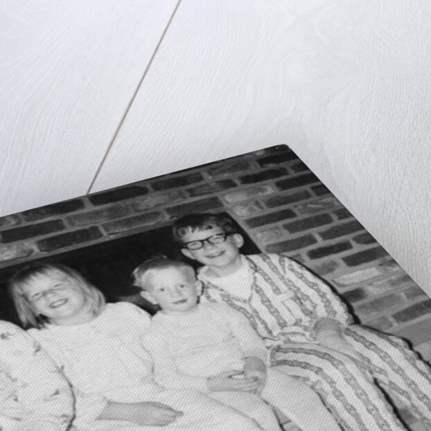 Siblings perch on a hearth in pajamas, ca. 1970. by Anonymous