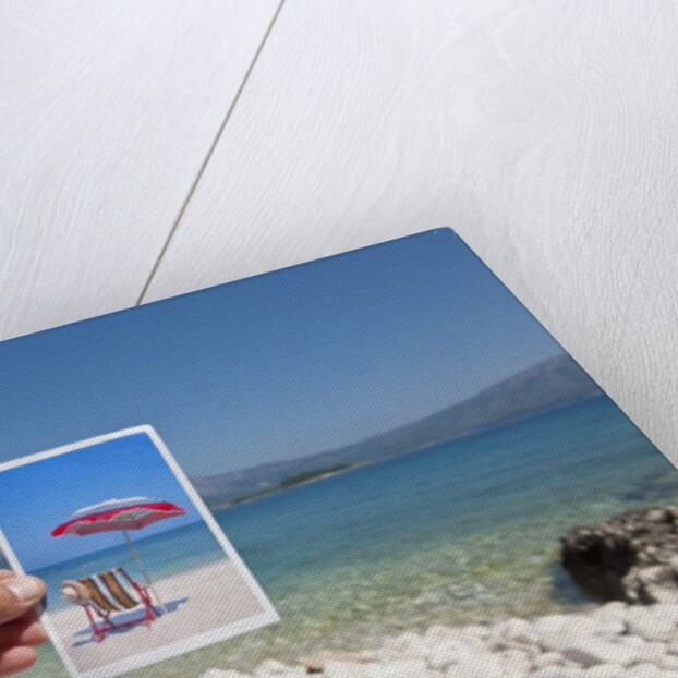 Hand holding photograph depicting deck chair and sunshade, Lumbarda, Korcula island, Croatia by Anonymous