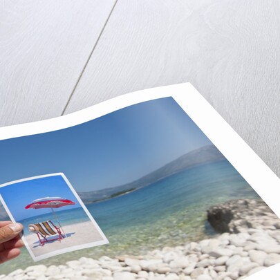 Hand holding photograph depicting deck chair and sunshade, Lumbarda, Korcula island, Croatia by Anonymous