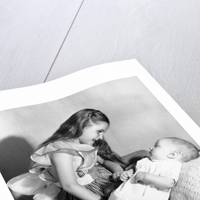 Big sister looks down on her baby brother, ca. 1948 by Anonymous