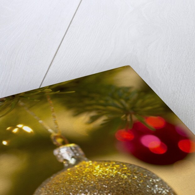Close-up of a golden hanging Christmas bauble on blurred tree by Anonymous