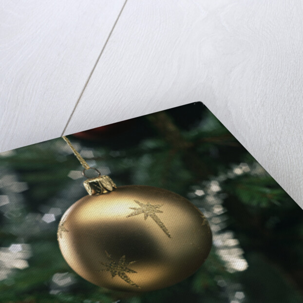 Close-up of a golden hanging Christmas bauble on blurred tree by Anonymous