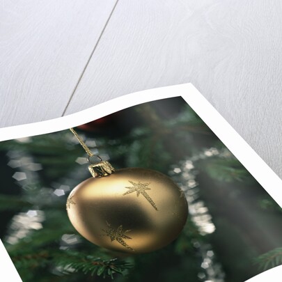 Close-up of a golden hanging Christmas bauble on blurred tree by Anonymous