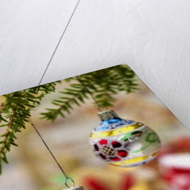Close-up of decorated hanging baubles against blurred gifts in the background by Anonymous
