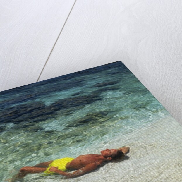 1990s Couple Sunbathing In Shallow Water At The Ocean's Edge by Anonymous