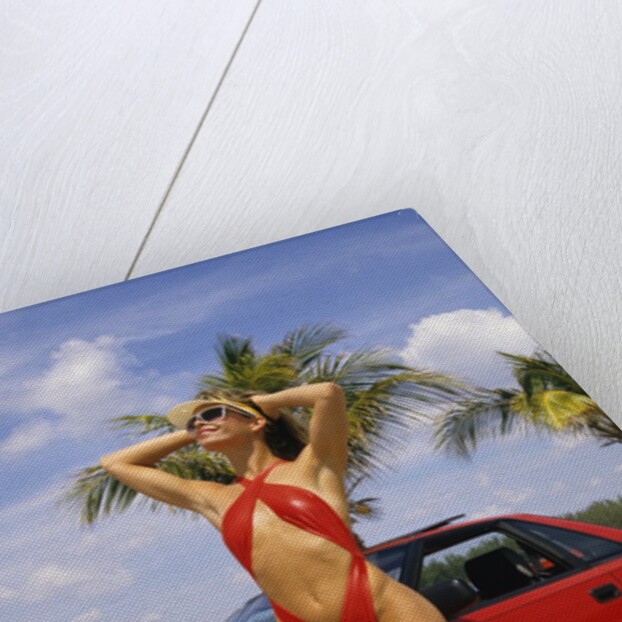 1980s Woman In Red Swimsuit In Front Of Red Sports Car by Anonymous